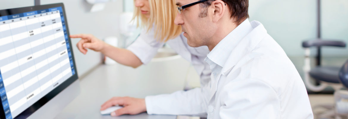 Smiling doctor sits in front of his laptop, checking his social media page for clinical trials recruitment.