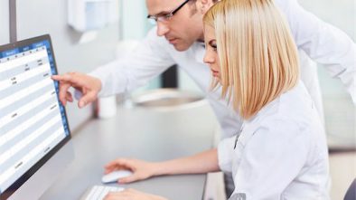 Two medical professionals analyze their local competition at a computer which is a critical step for new patient acquisition.